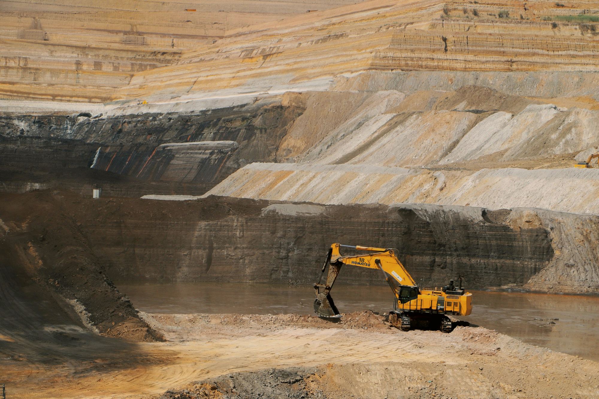 A yellow excavator in an open pit