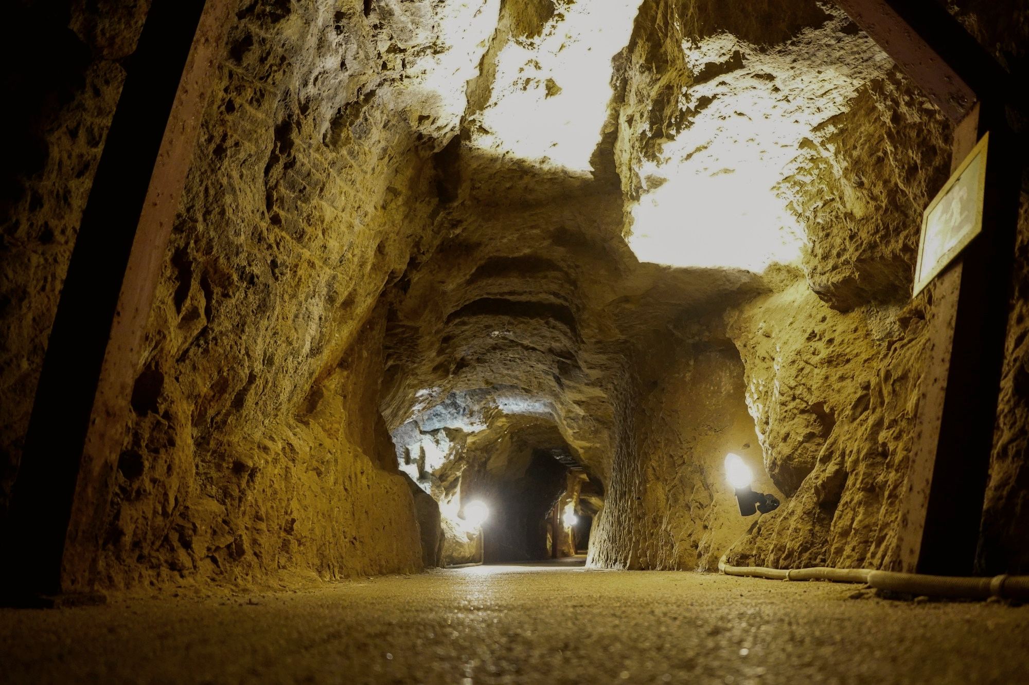 A lit pathway running through a rough-cut mine tunnel