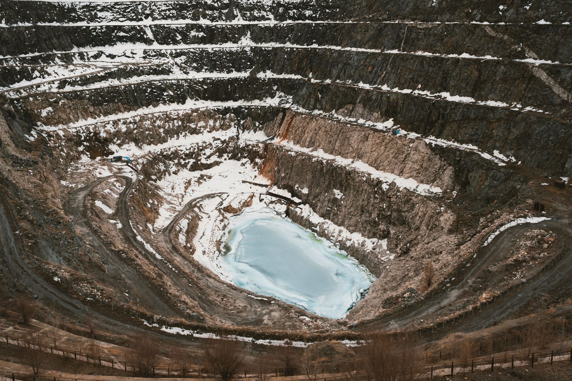 Aerial view of an open-pit mine with water at the base
