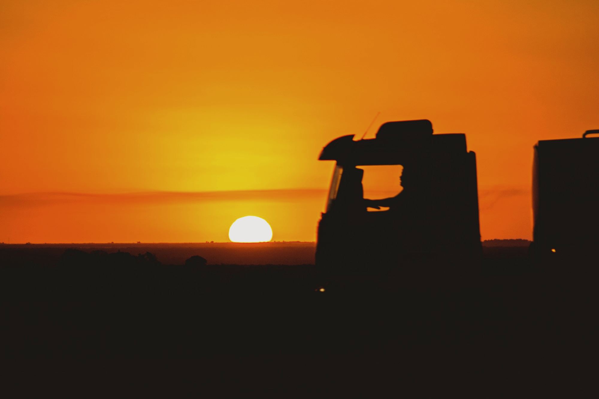 Silhouette of a truck against an orange sky